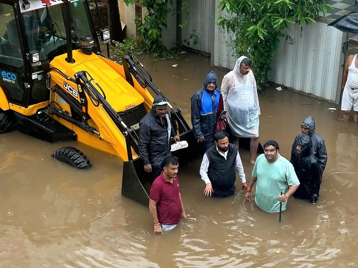 रस्त्यावर पाणी साचल्याने जेसीबीच्या साह्याने नागरिकांना तातडीने मदत करताना
